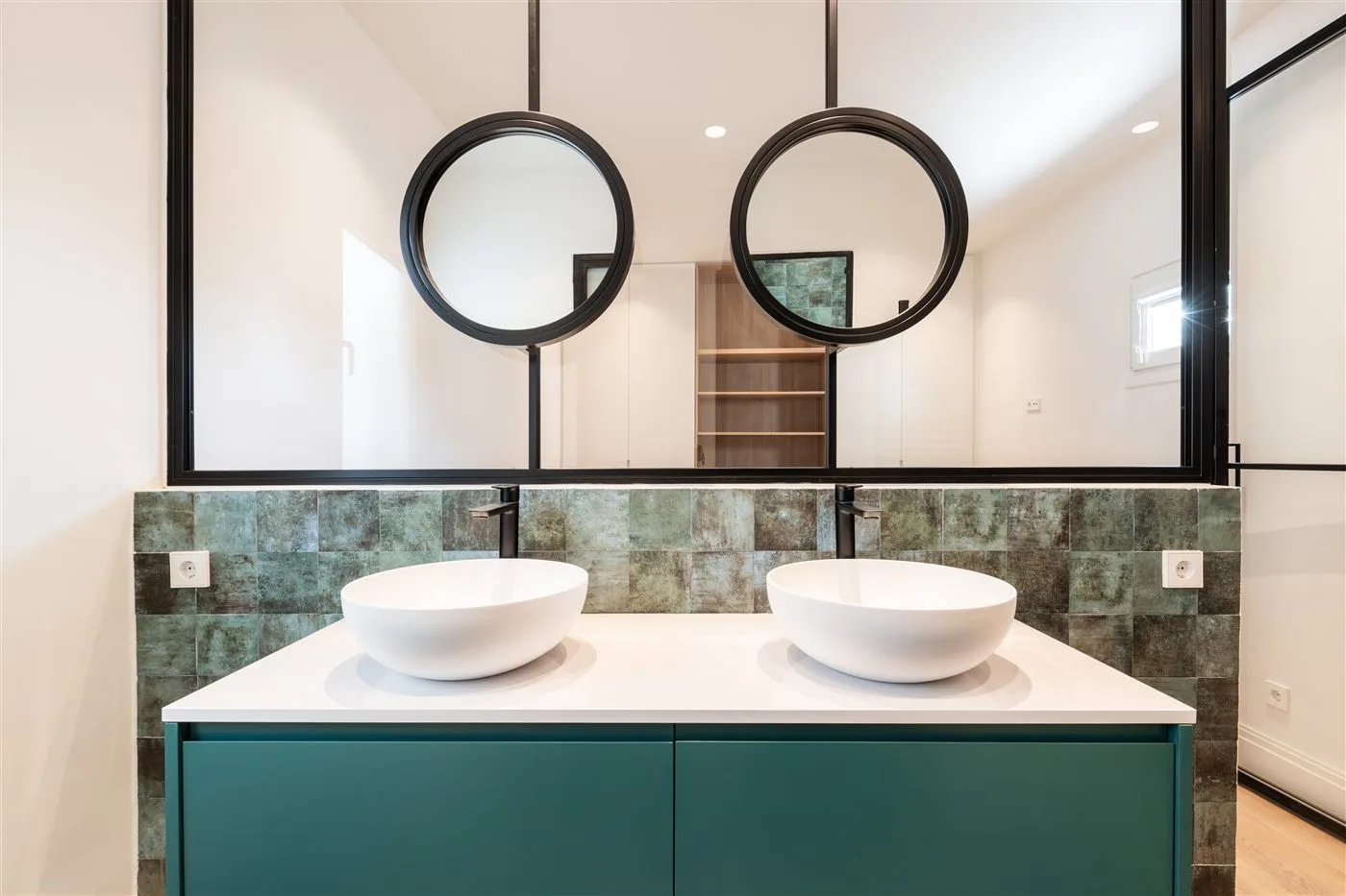 Reforma de baño con doble lavabo verde y espejos redondos en Madrid