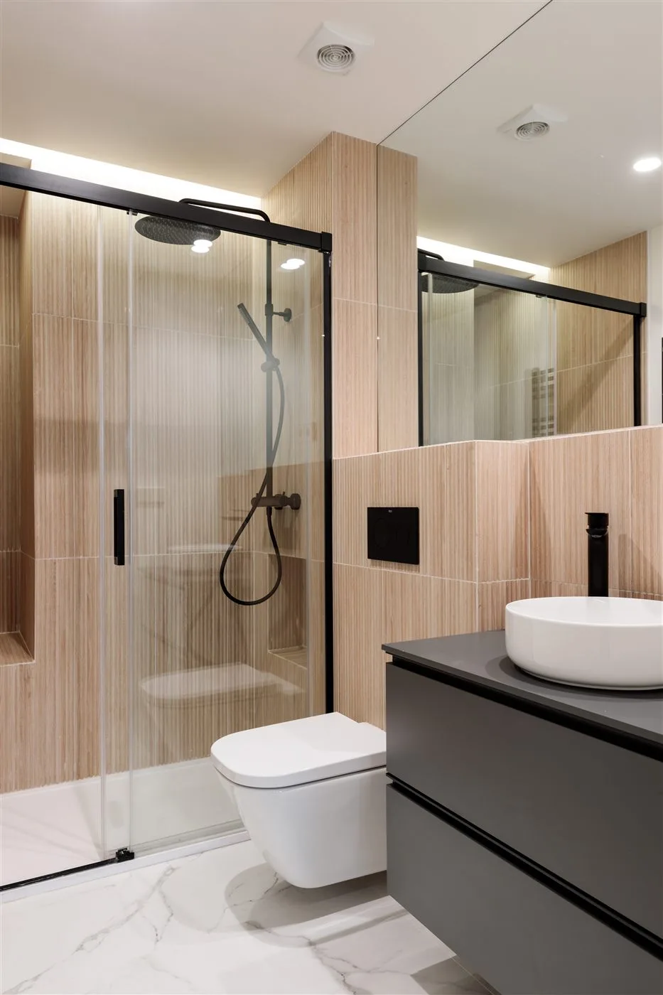 Reforma de baño con revestimiento de madera y grifería negra en Madrid