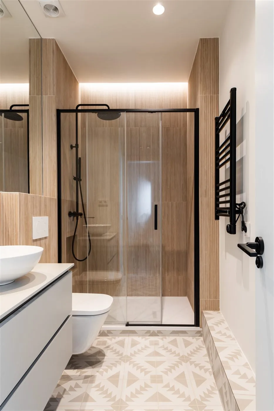 Reforma de baño con revestimiento de madera y suelo geométrico en Madrid
