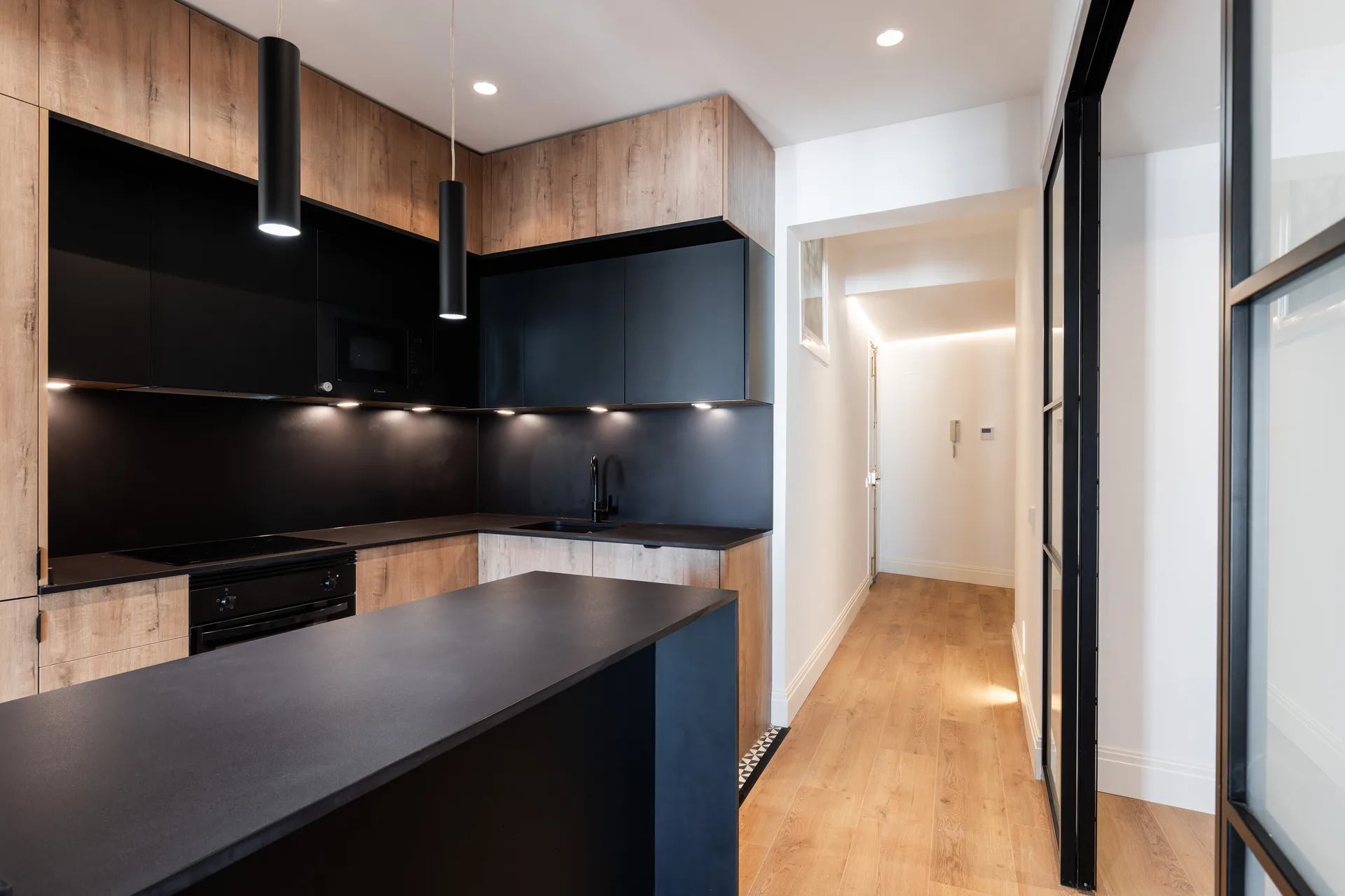 Reforma de cocina negra con madera y encimera negra con isla en Madrid